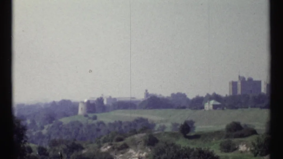 1967 Ottawa view across green slopes and trees toward distant urban buildings and a castle-like structure on the horizon.