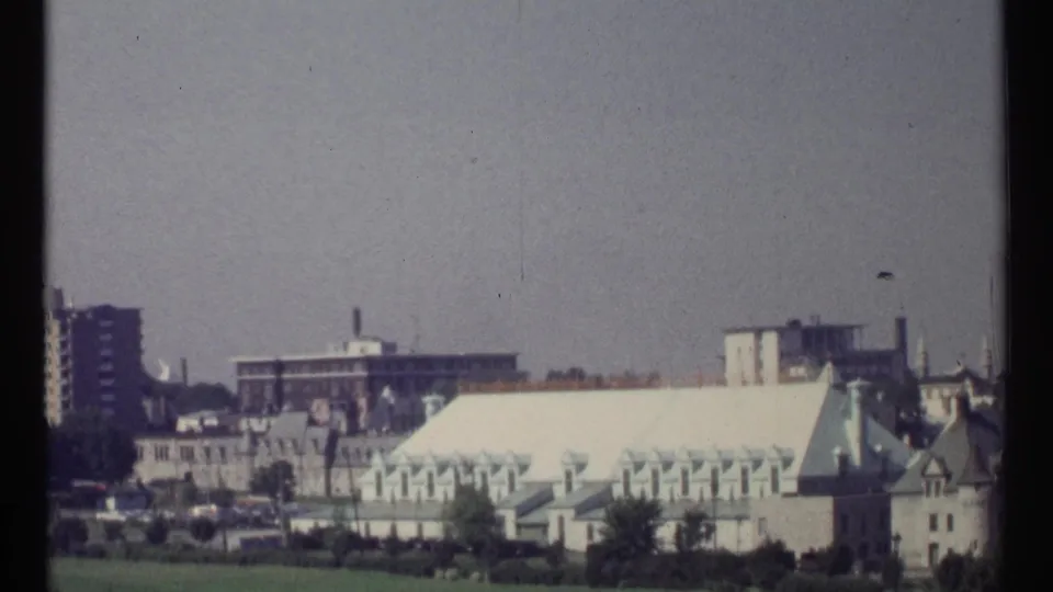 1967 Ottawa view shifting from parkland to pale-roofed institutional buildings and nearby urban structures.
