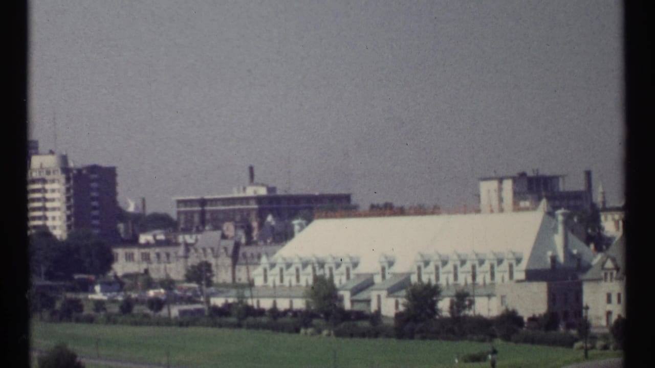Wide city view with green-roofed buildings, trees, and high-rises.