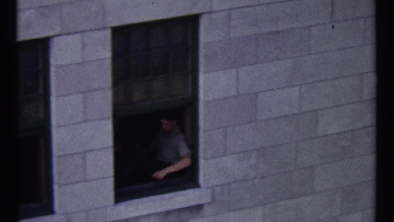 Man seated at an open window in a stone building.