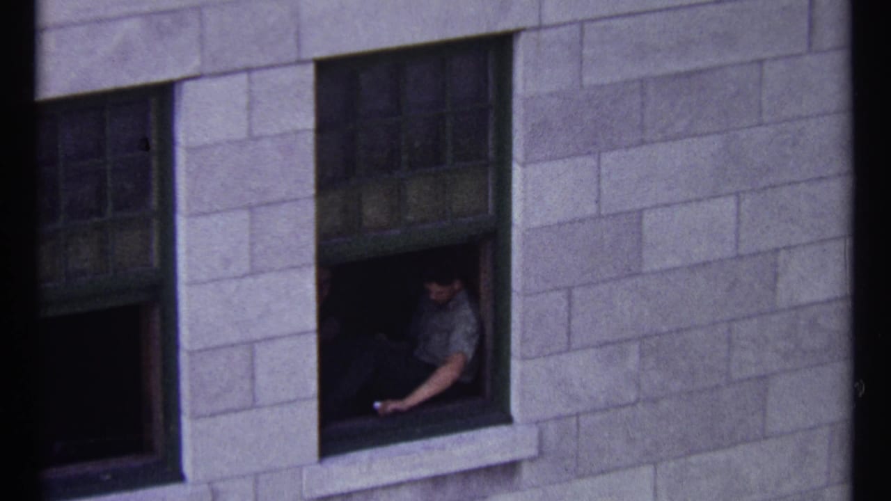 Man leaning near an open window on a stone facade.