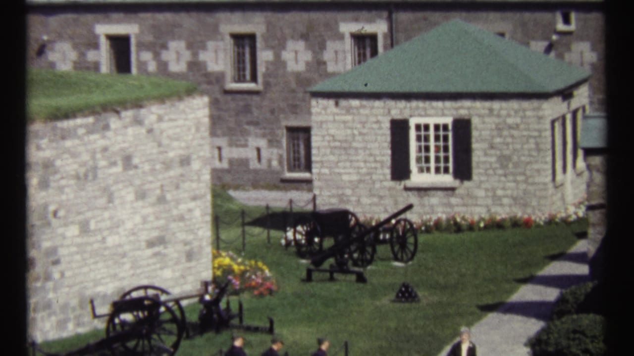 Ottawa fortress courtyard in 1967 with lawn-mounted cannons, stone masonry, flowers, and a green-roofed structure in bright sun.