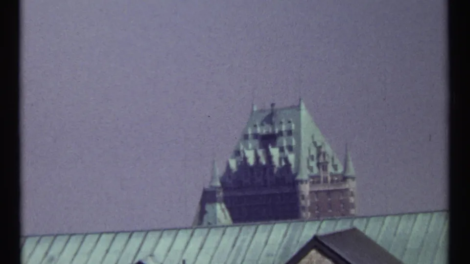 1967 Ottawa frame with a distant château-style green roof partly obscured by a foreground roof, captured in soft home-movie focus.