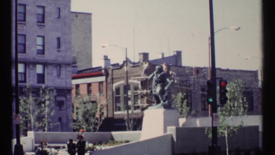 1967 Ottawa urban view showing a public monument at an intersection, traffic lights, street poles, and surrounding buildings.