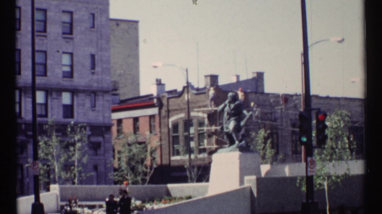 Civic statue beside a downtown street and traffic signal.