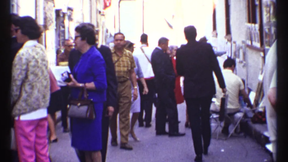 Ottawa 1967 8mm frame of pedestrians in a shopping-plaza passage, with display racks and people walking in both directions.