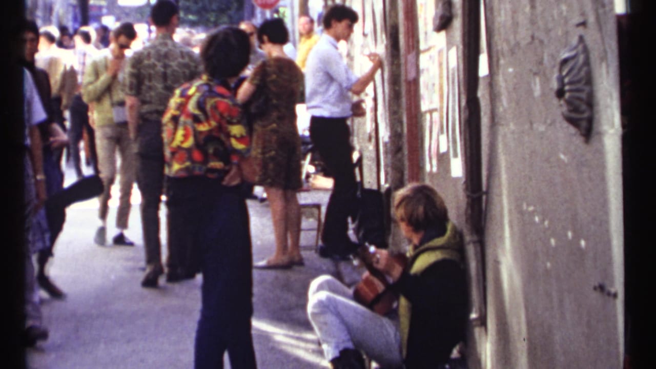 Pedestrians gather near exterior displays while a seated guitarist plays beside the wall.