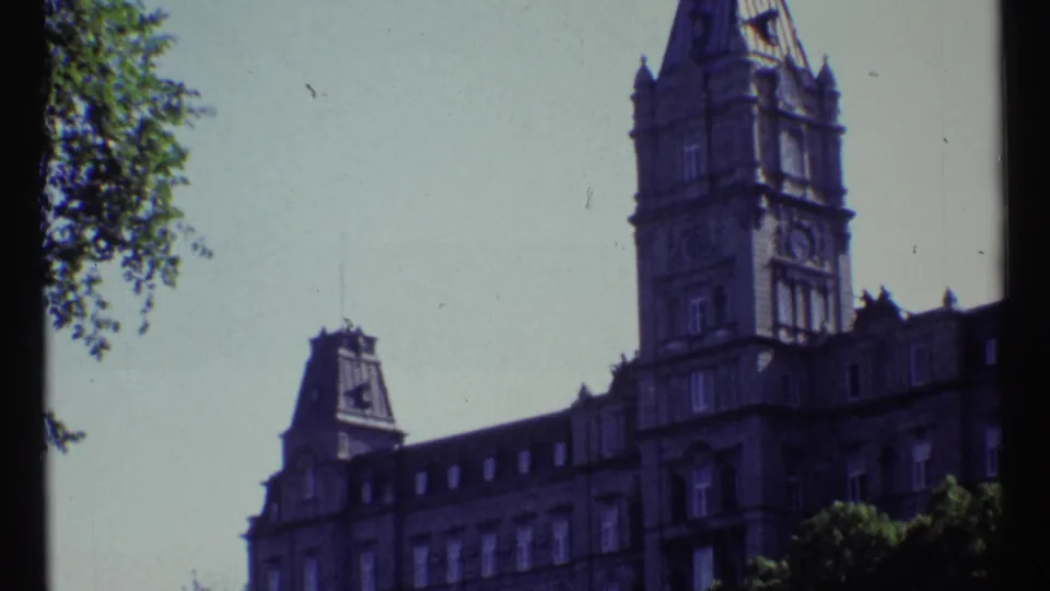 1967 Ottawa frame holding on Château Laurier's tower and upper facade, with tree foliage along the left edge.
