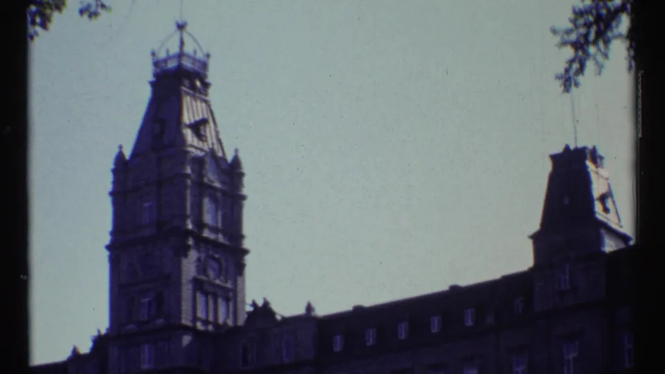 1967 Ottawa frame showing Château Laurier's tower and roofline from below, with tree foliage at the frame edges.