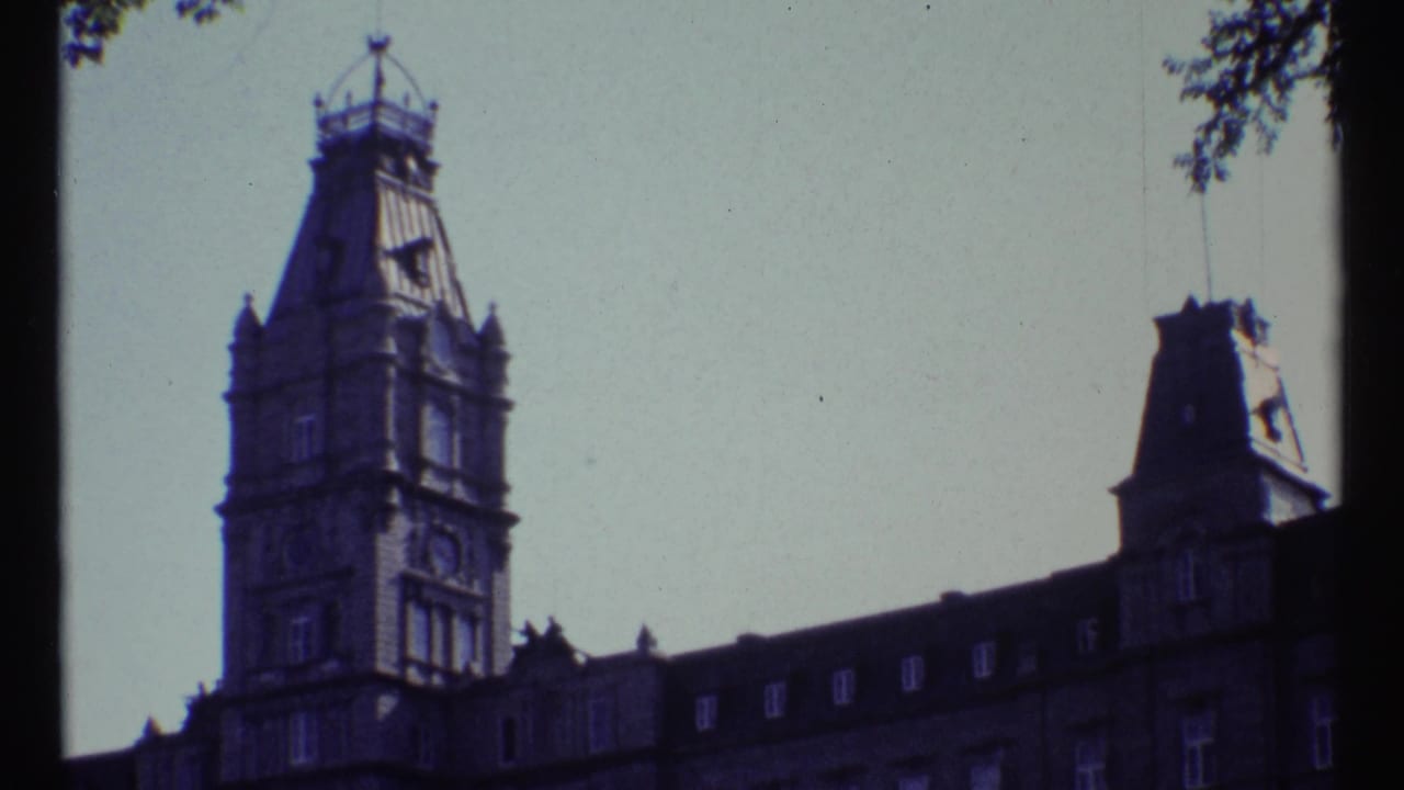1967 Ottawa frame with the clock tower centered left and a long mansard roof extending across the scene beneath a bright, washed sky.