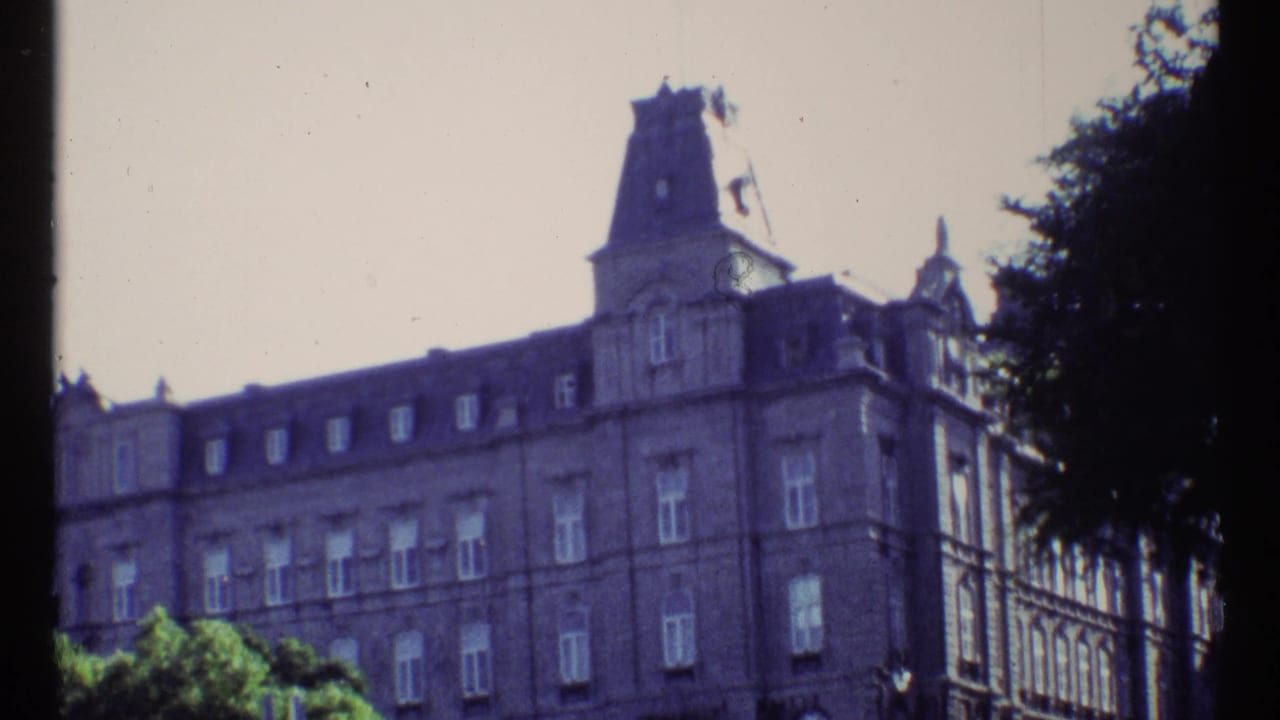 Grand building facade with mansard roofline and trees along the right edge.