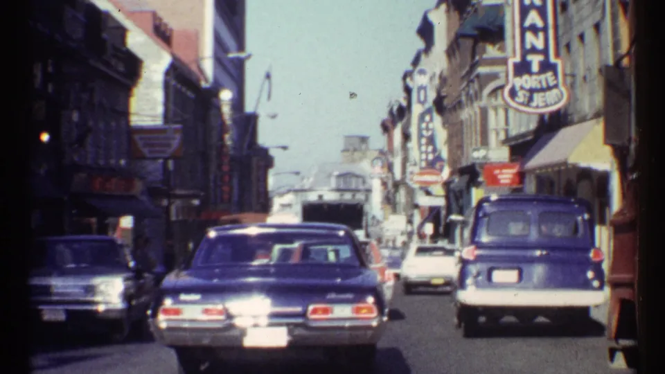 1967 Ottawa commercial street with vintage cars, a blue van, pedestrians, and visible Porte St. Jean signage.