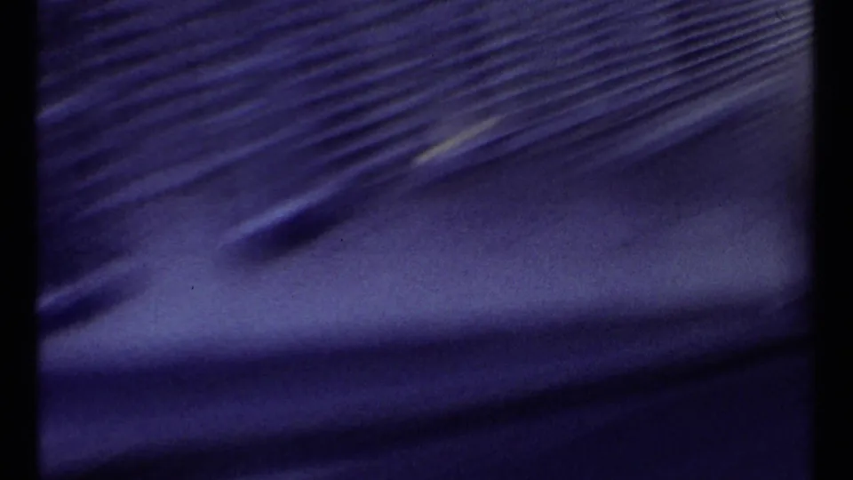 Opening 8mm frame with dark blurred film area at left and a distant bridge view beginning at the right edge.