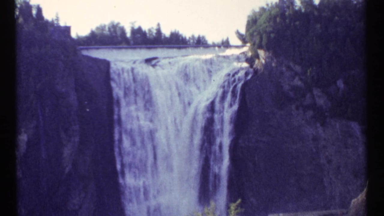 1967 Ottawa 8mm frame showing a waterfall spilling over a broad ledge into a rocky gorge with trees above.