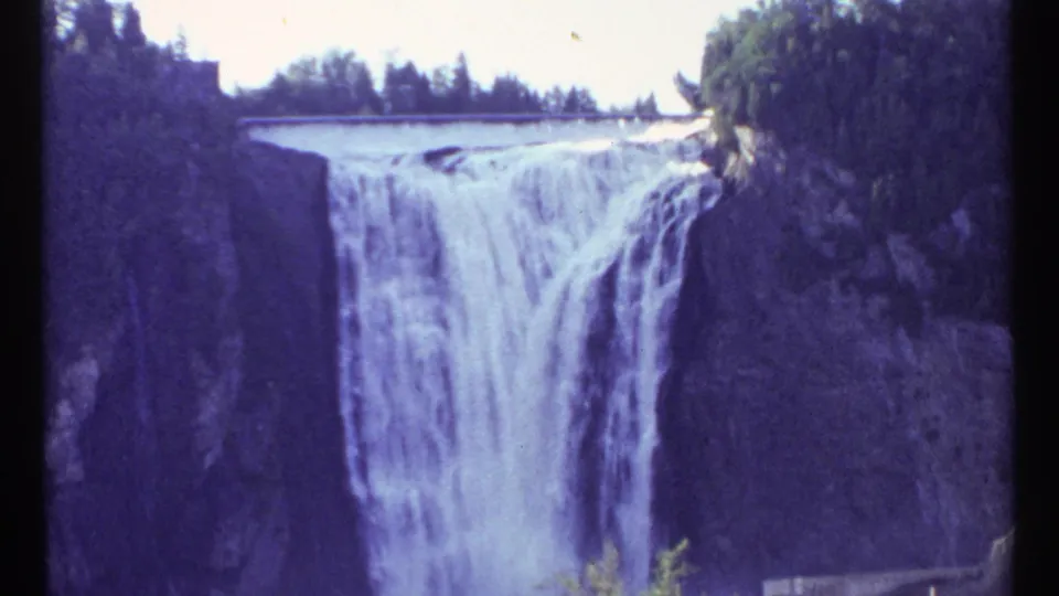 1967 Ottawa 8mm frame showing the waterfall from a steady visitor viewpoint, with cliffs and trees surrounding the drop.