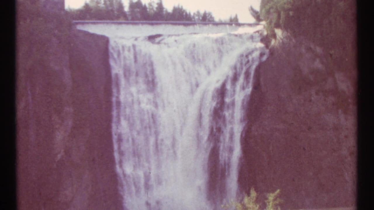 Waterfall framed between dark rocky sides and trees above.