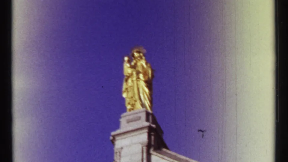 1967 Ottawa 8mm frame showing a gilded religious statue on a stone pedestal, cropped against the sky.