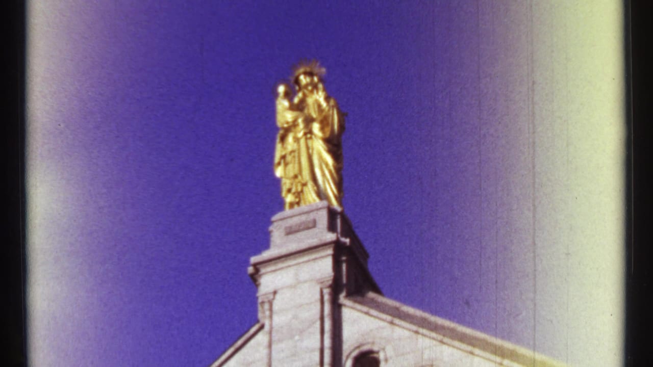 Golden statue and stone building corner filmed from below.