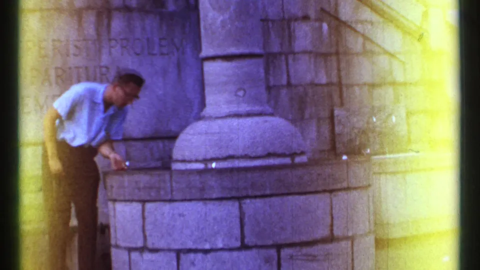 At the end of the 1967 Ottawa clip, the man straightens beside the stone fountain with carved stone architecture behind him.
