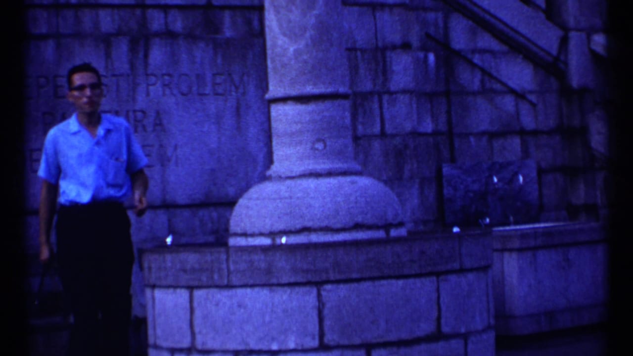 Adult man in sunglasses standing beside a stone monument wall.