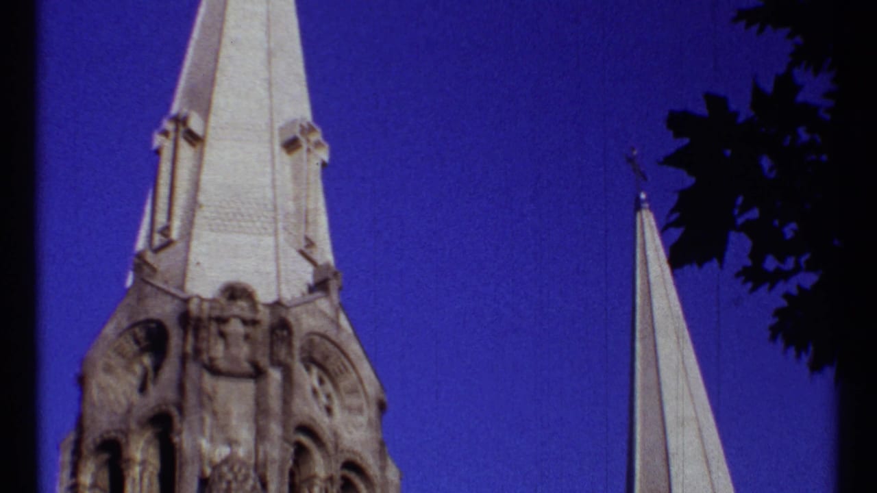 Tall church steeple and stone tower seen from below against a purple-blue sky.