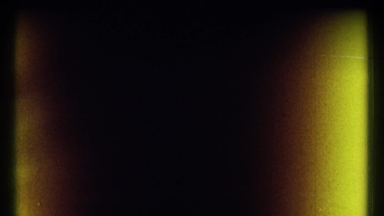 Mostly dark film frame with yellow and orange vertical light leaks at the edges.