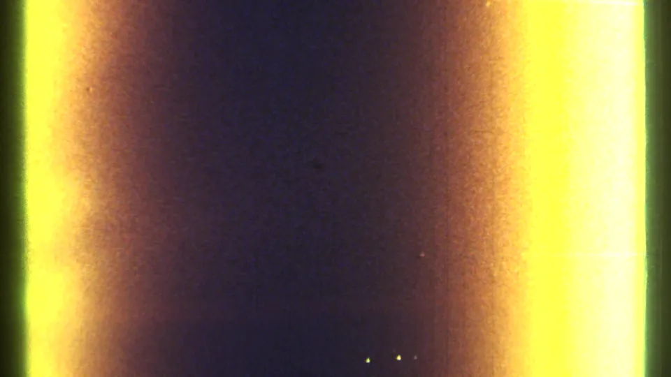 8mm frame from the Ottawa clip with mostly dark exposure and broad yellow film-edge flares at left and right.