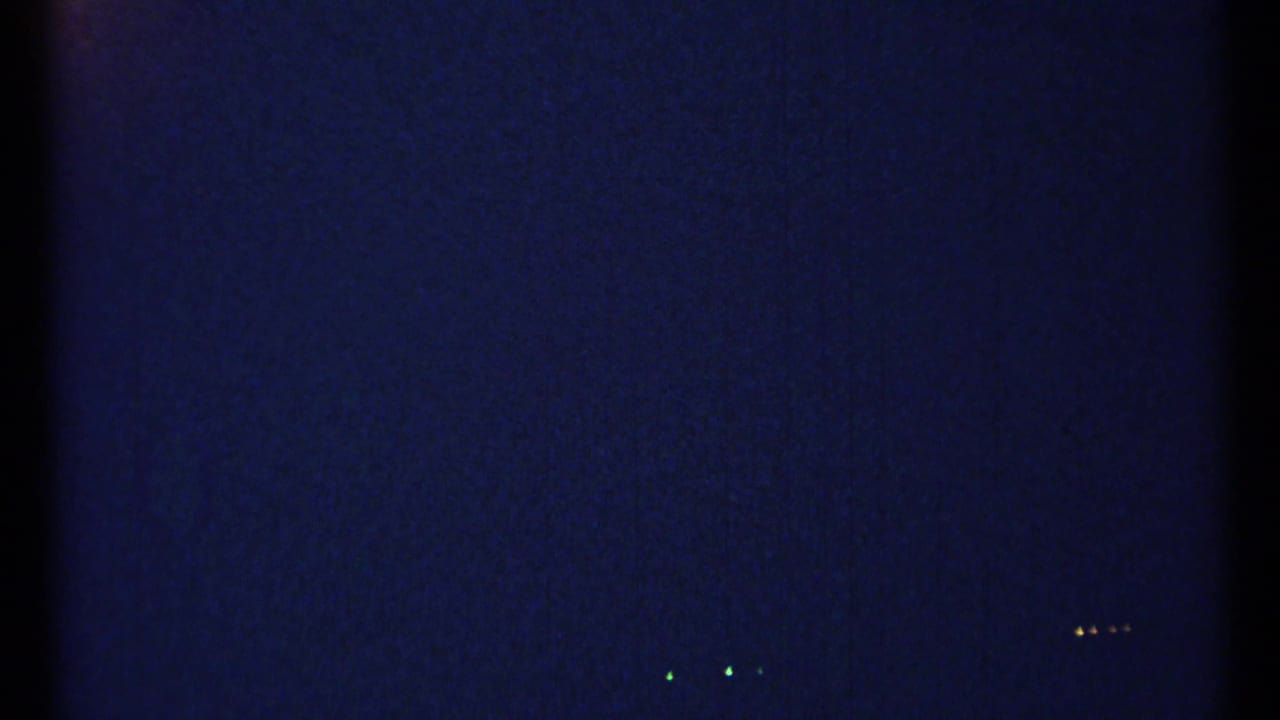Dark blue film frame with faint specks and small distant light points.