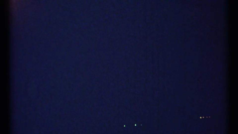1967 Ottawa 8mm frame showing dark blue grain, faint green and yellow specks, and a mostly abstract exposed-film field.