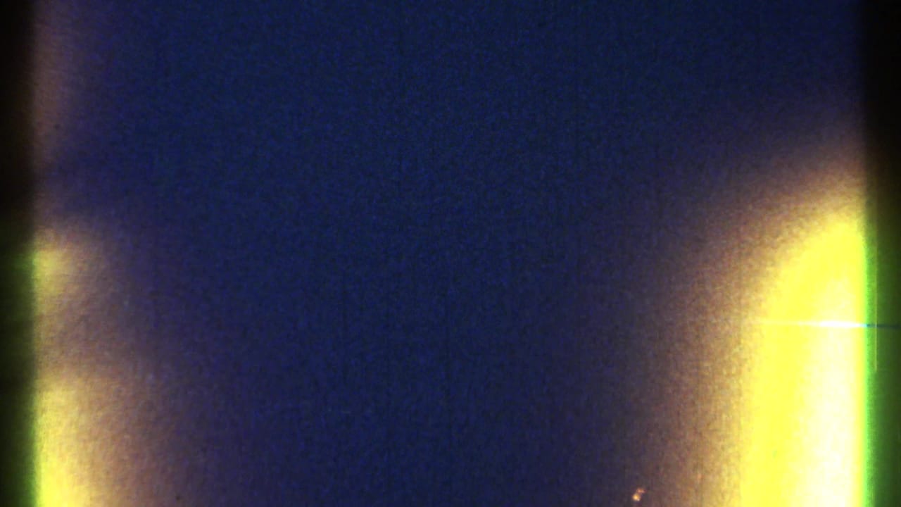 Dark blue film texture with a narrow vertical flare and bright yellow edge burn.
