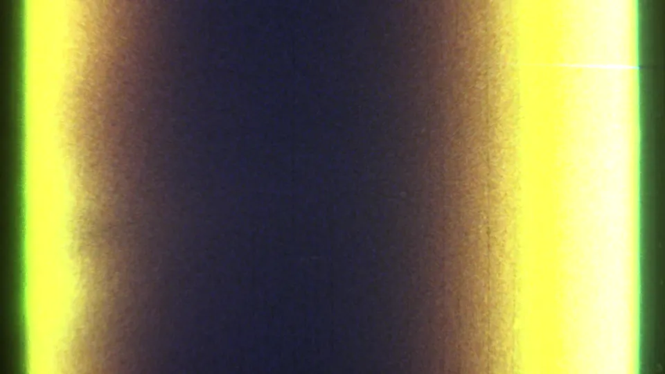 1967 Ottawa 8mm frame showing a dark blue grain field, soft orange flare, and a bright yellow-green light leak at the right border.
