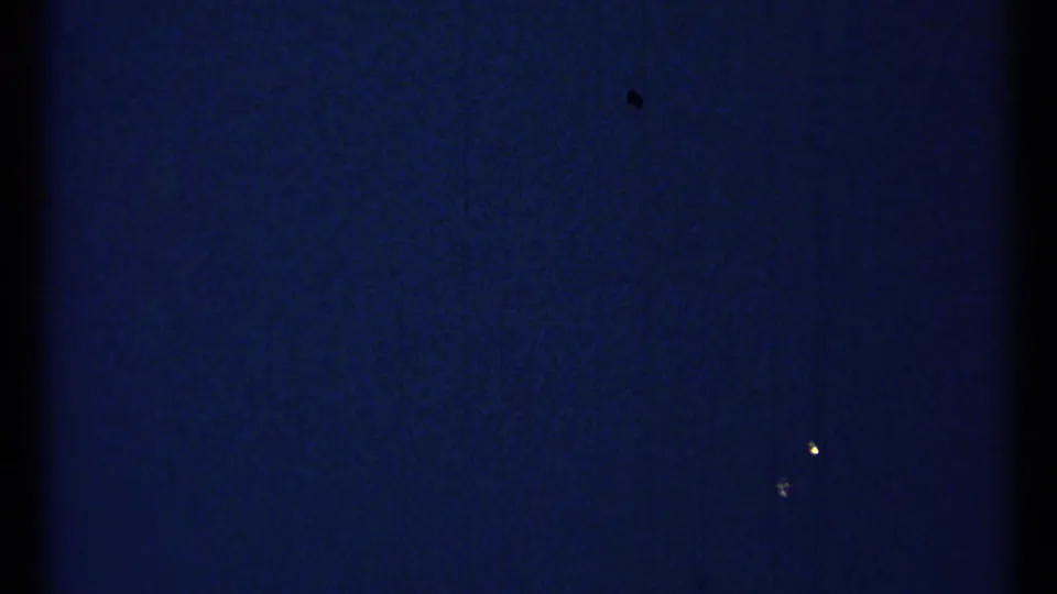 Dark opening frame from 1967 8mm footage with visible grain, tiny light specks, and little discernible scenery.
