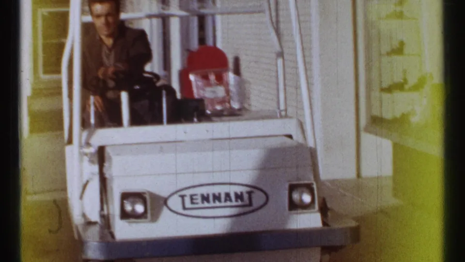 A closer 1967 Ottawa view shows the driver at the controls of a white Tennant cart moving along a shop-lined sidewalk.
