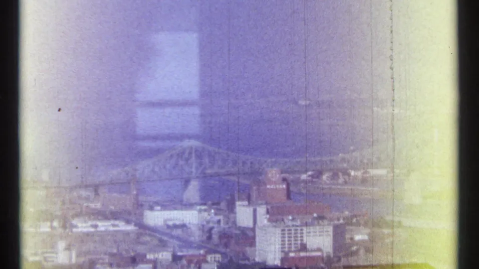 Elevated Ottawa view from 1967 showing a river bridge, city buildings, and a tower-like structure through faded 8mm color.