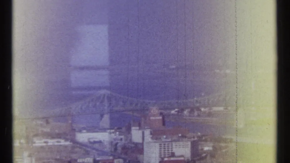 1967 Ottawa skyline view with a bridge spanning the river, low city buildings, haze, and pronounced 8mm scan marks.