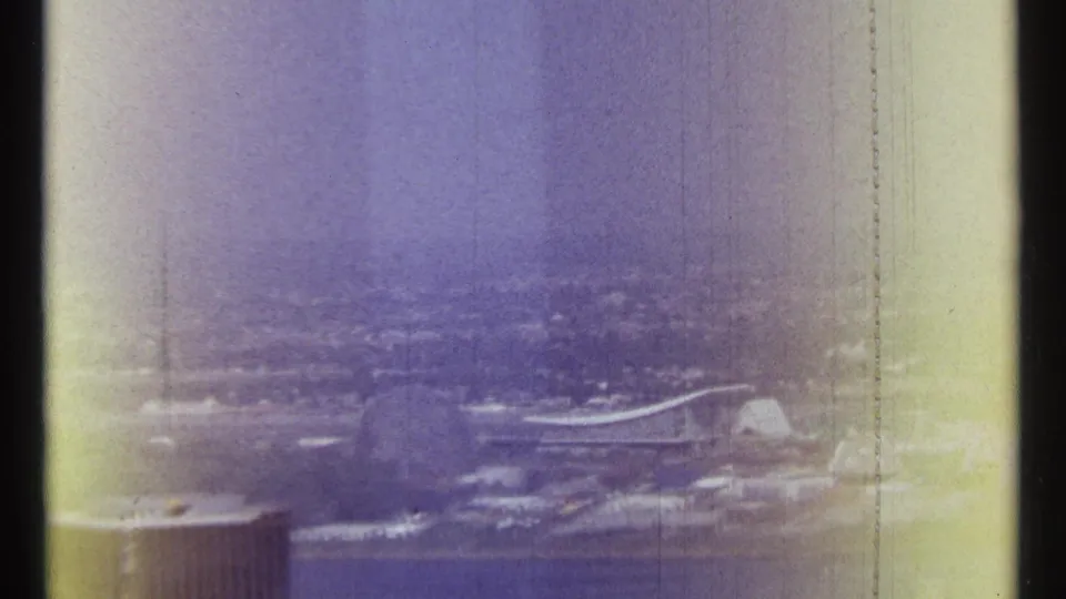 1967 Ottawa home-movie frame showing a soft elevated view across the riverfront, with a foreground building edge and distant urban landscape.
