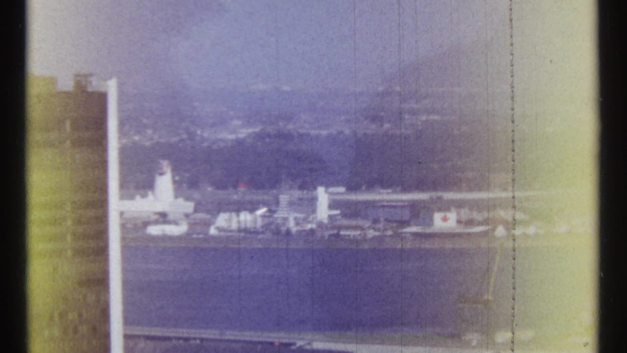 Distant waterfront buildings and a tall pale structure beside a broad river.