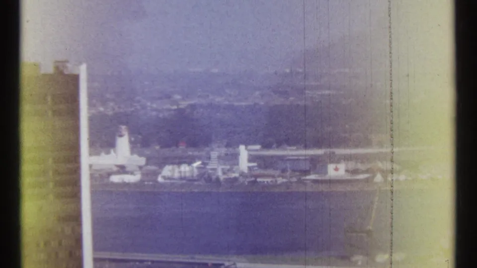 1967 Ottawa riverfront view with distant industrial structures, a tall vertical form, and faded blue-purple 8mm exposure.