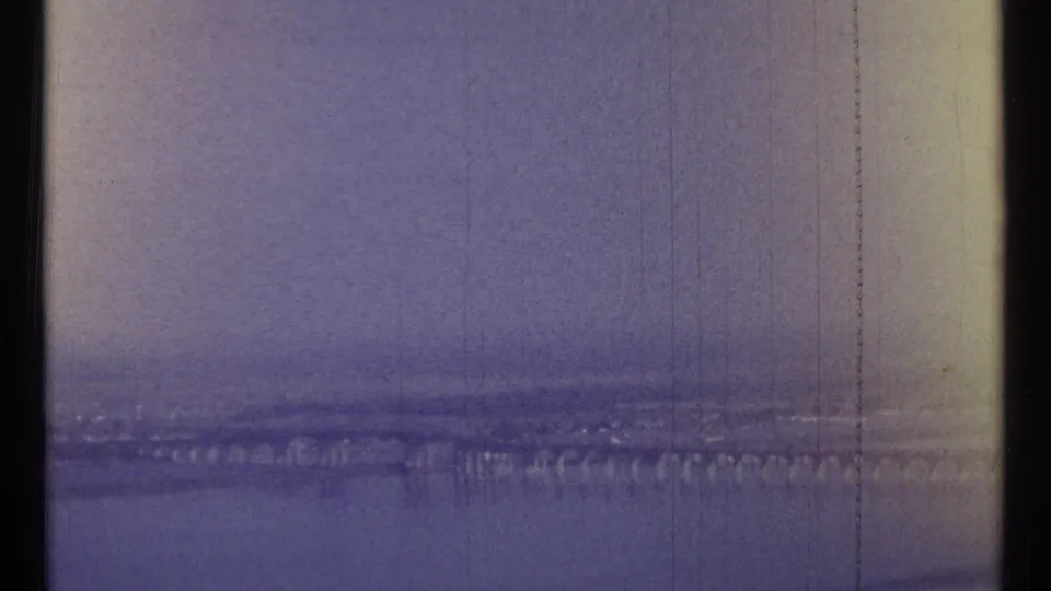 1967 8mm view of a long bridge over water near Ottawa, with strong color shift and visible scratches.