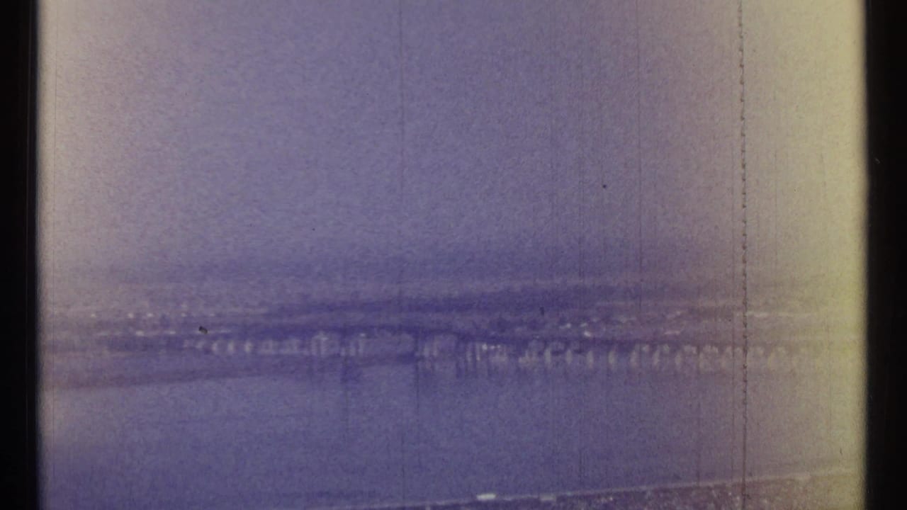 Distant skyline and bridge seen through a faded, scratched aerial frame.