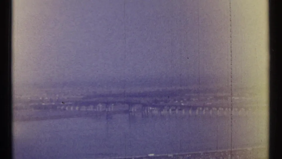 Faded 8mm frame of Ottawa in 1967, with a river crossing and low skyline visible through haze and film wear.