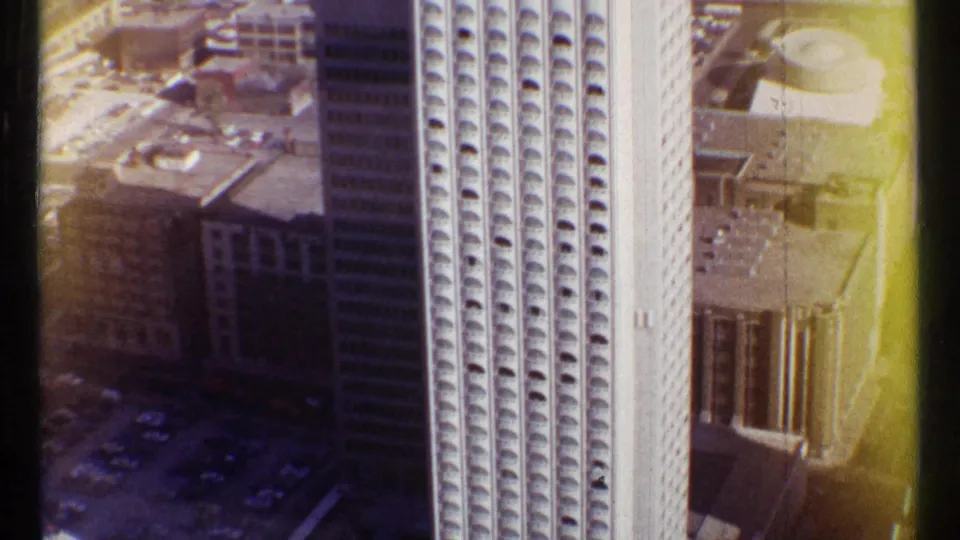 Aerial 8mm view of a tall Ottawa high-rise in 1967, with repeating window arches and surrounding downtown rooftops.
