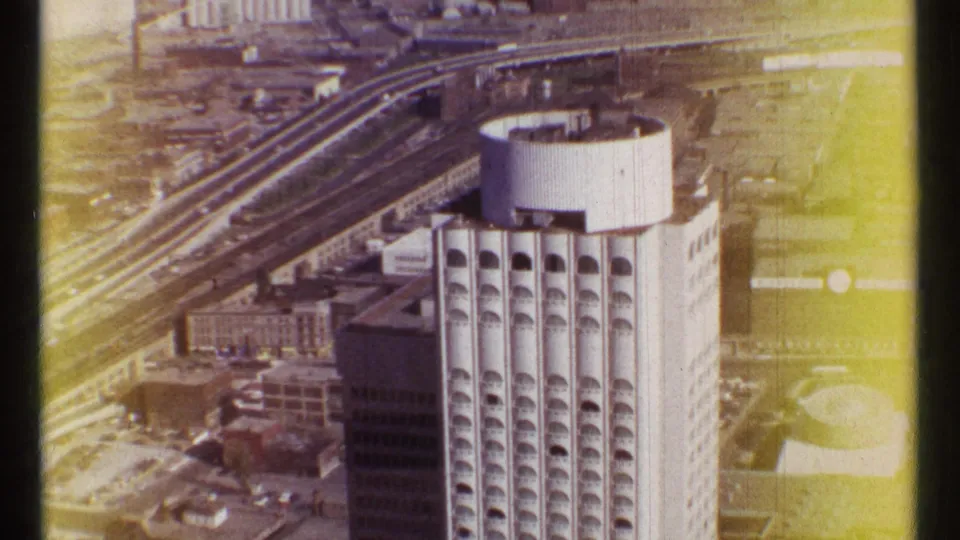 1967 Ottawa aerial view showing a tall high-rise with arched window bays, a circular rooftop structure, and surrounding urban infrastructure.