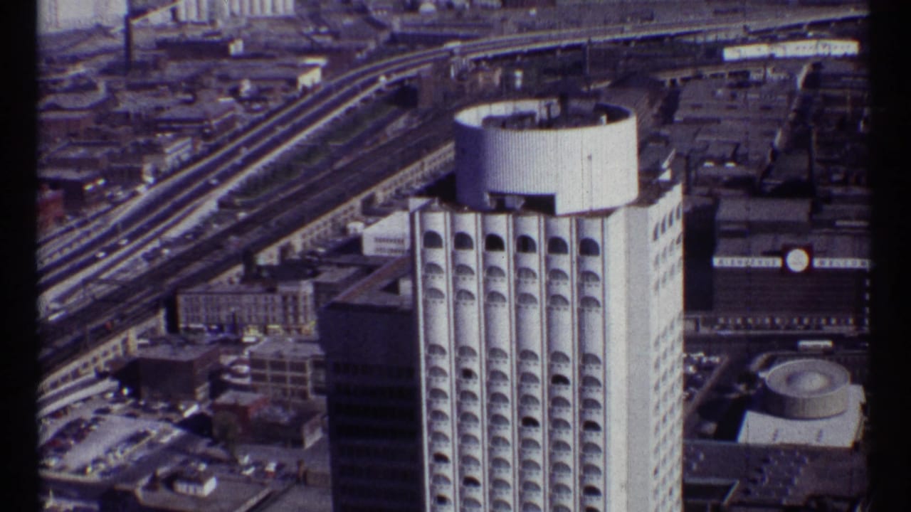 1967 Ottawa aerial frame with the high-rise centered, elevated transport corridors behind it, and low urban buildings around the site.