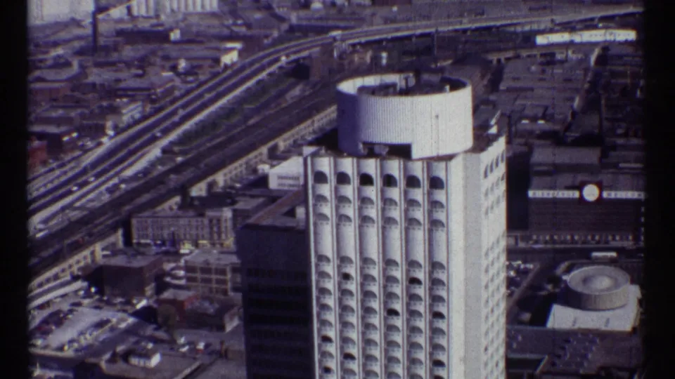 1967 Ottawa aerial frame with the high-rise centered, elevated transport corridors behind it, and low urban buildings around the site.