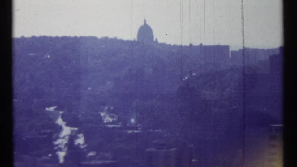 1967 Ottawa cityscape frame with a distant domed silhouette, layered urban skyline, dark foreground structures, and vertical film wear marks.
