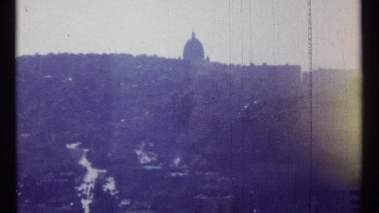 Distant dome on the horizon above trees and a road in a hazy city view.