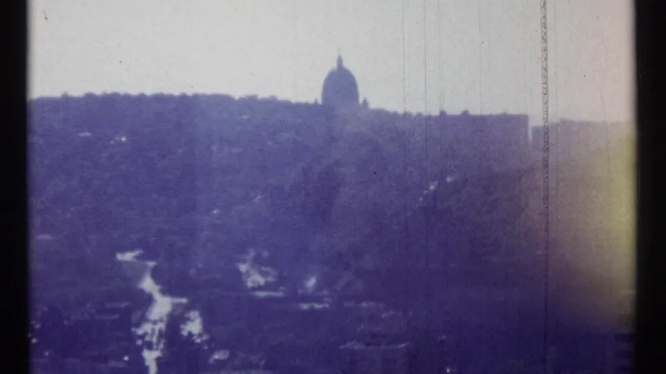 Ottawa skyline view from 1967 with a dome on the ridge line, wooded foreground, road traces, and visible 8mm film wear.