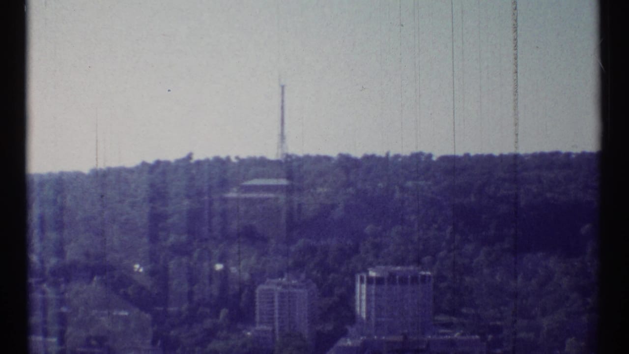 1967 Ottawa frame with a wooded ridge, distant high-rise structures, and a slender communications tower on the skyline.