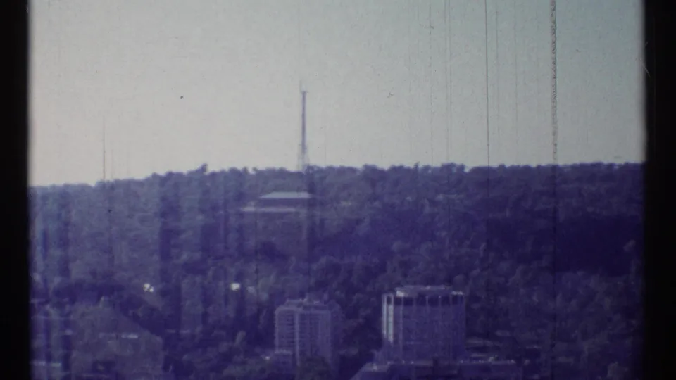 1967 Ottawa frame with a wooded ridge, distant high-rise structures, and a slender communications tower on the skyline.